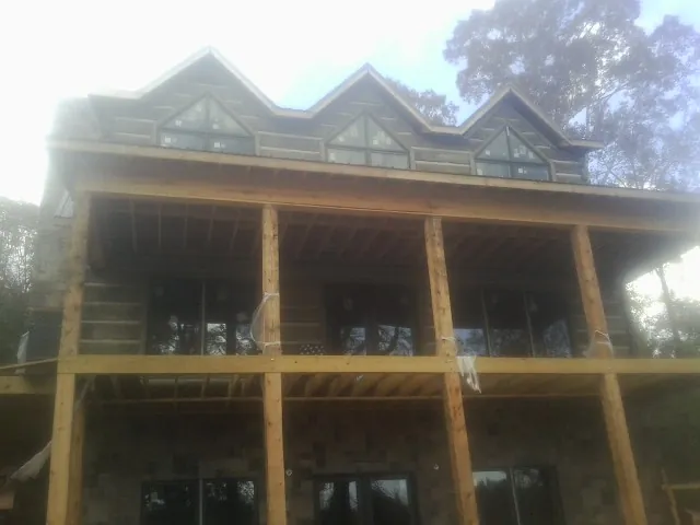 Dormers and porch framing on a large log home under construction — Roof Coating work by our crew in Westhampton Beach