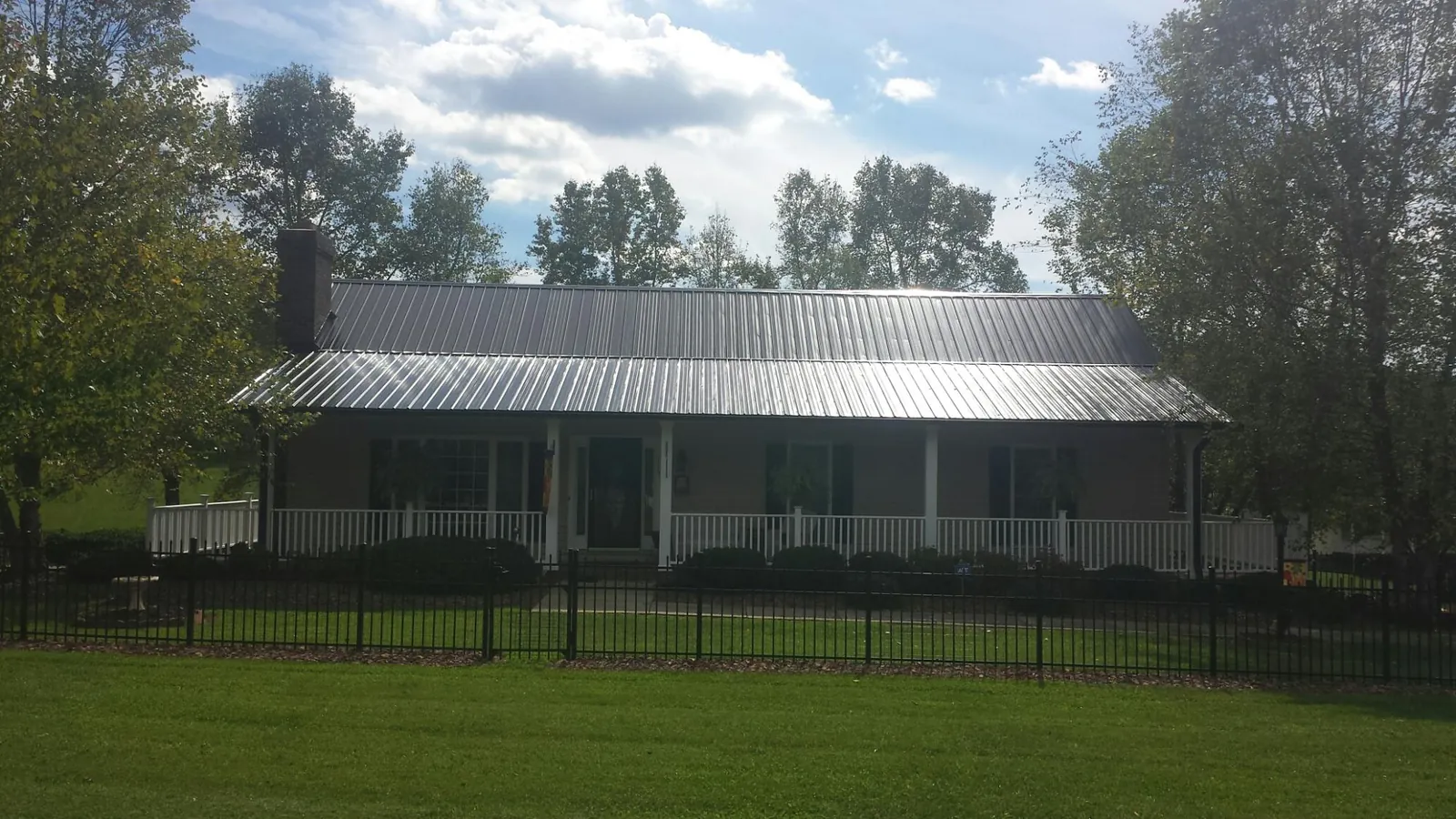 Gray metal roof on a brick ranch with a full width front porch — Gutter Guard Installation work by our crew in Westhampton Beach