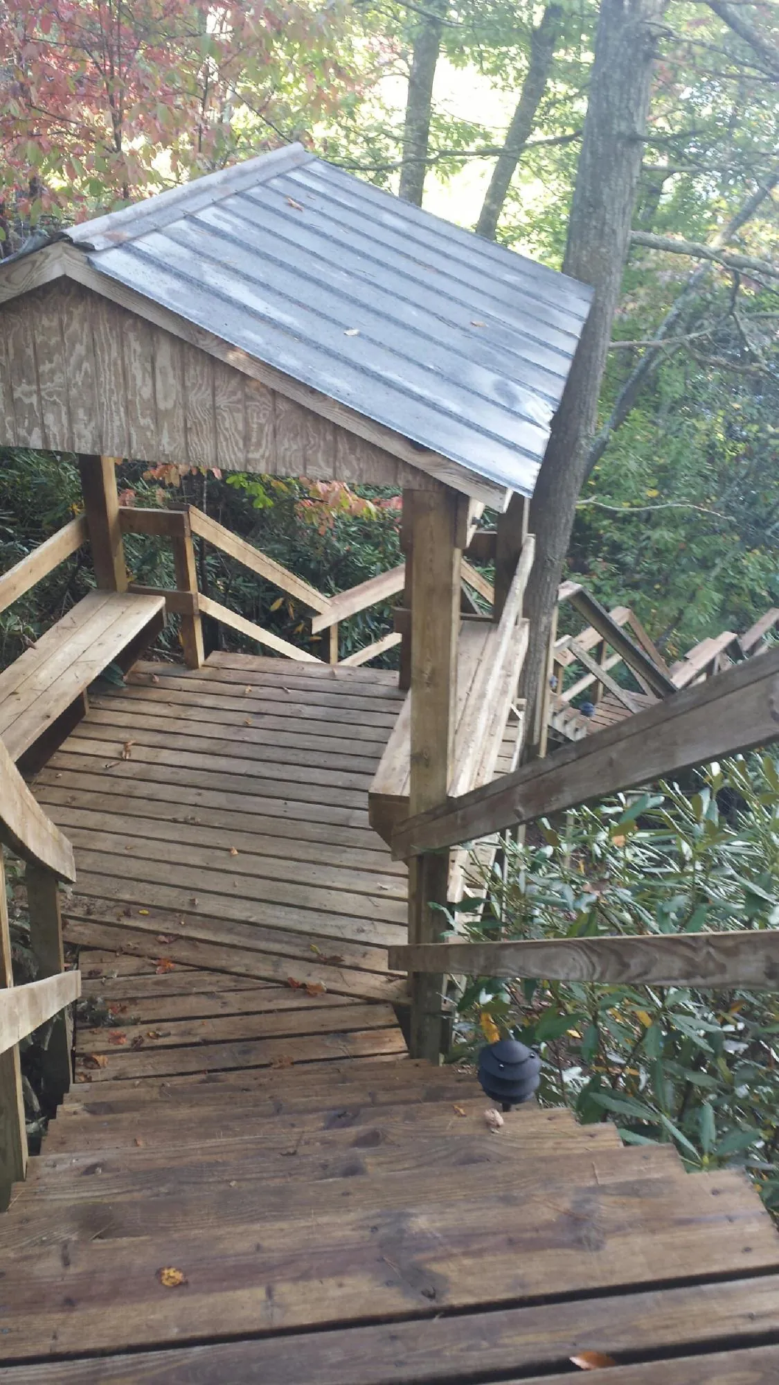 Metal roofed shelter over wooden steps on a wooded walkway — Skylight Repair & Installation work by our crew in Westhampton Beach