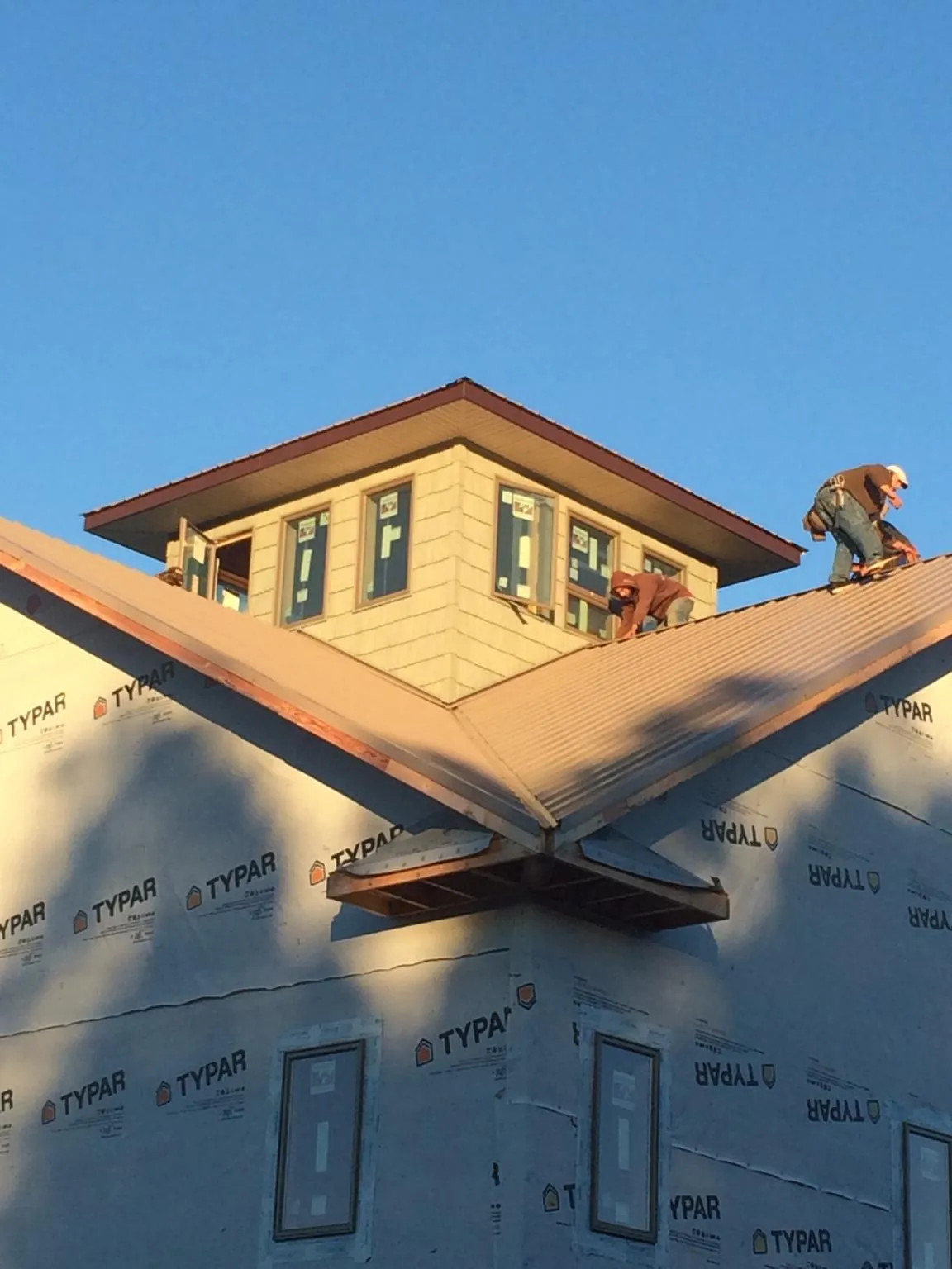 Roofers working around a rooftop cupola on a new metal roof at sunset — Roof Waterproofing in Westhampton Beach by Roofing Brothers